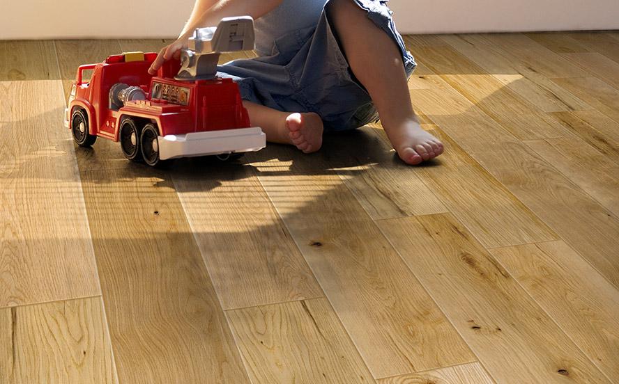 Kid playing with a toy truck on wood flooring