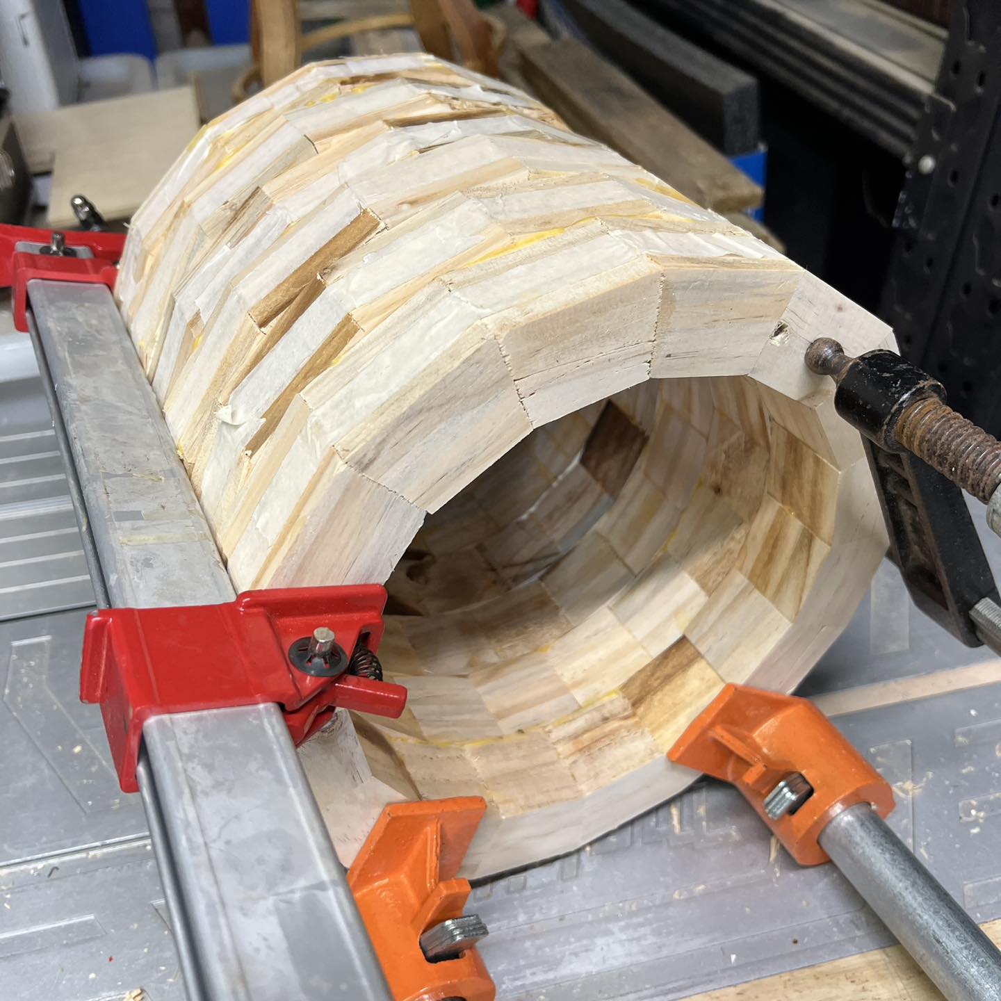 A cylinder of wood being glued together and held together with clamps