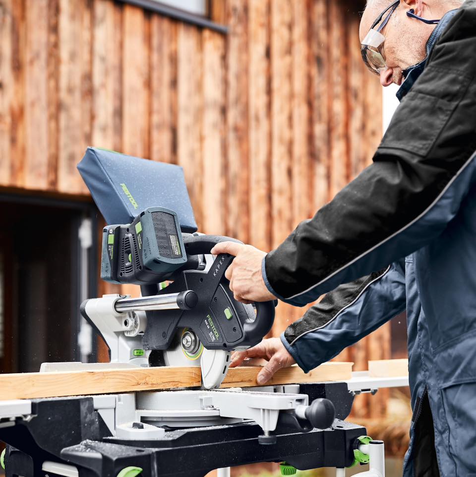 Person cutting wood with a table saw outside