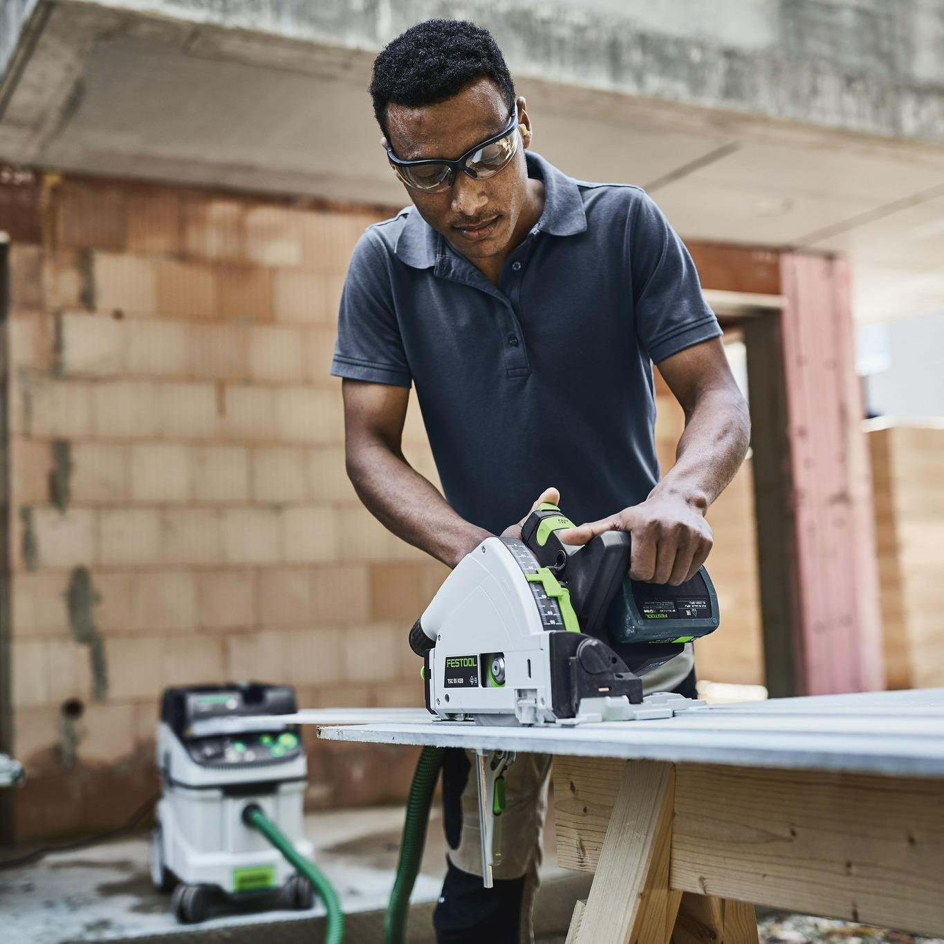 Man sawing with a vacuum attachment in the background