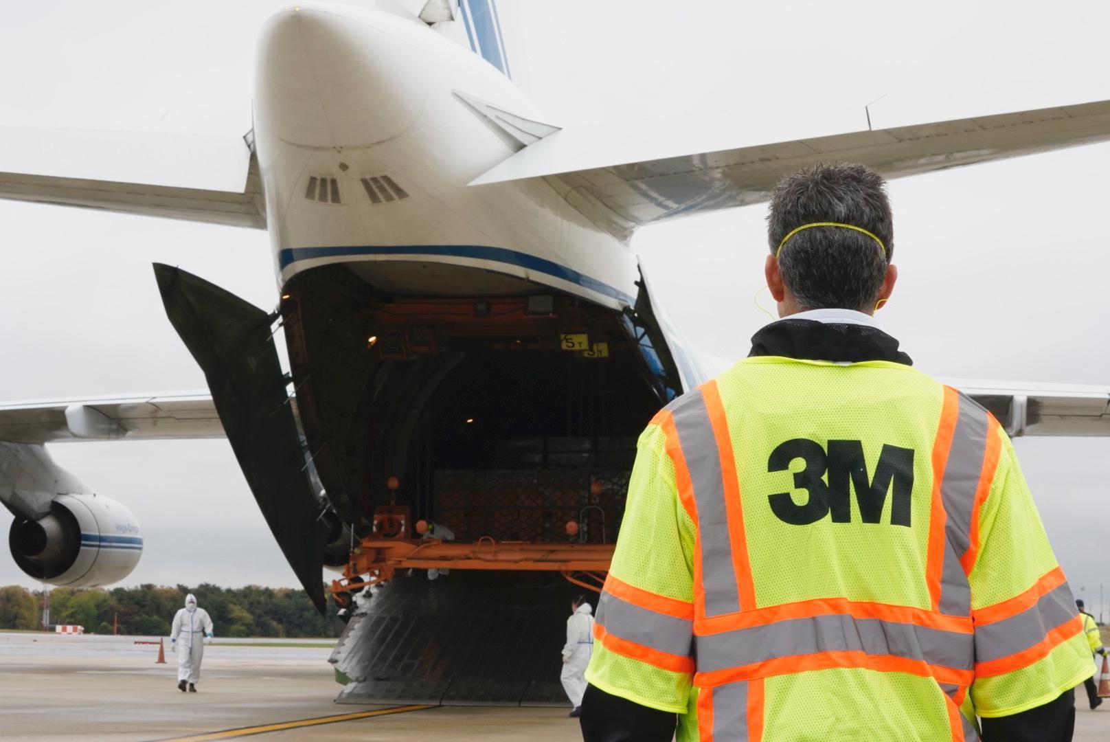 Person wearing a 3M safety shirt in front of a cargo airplane