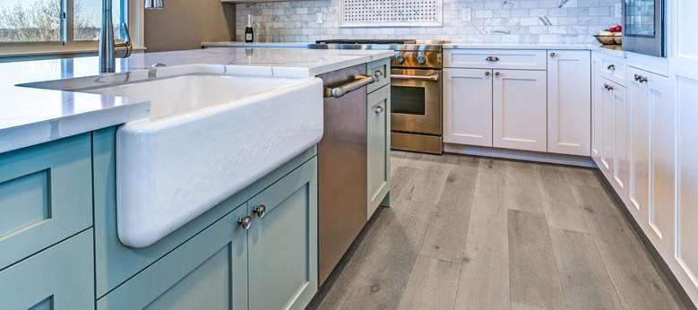 Kitchen with teal and white cabinets and gray wood flooring