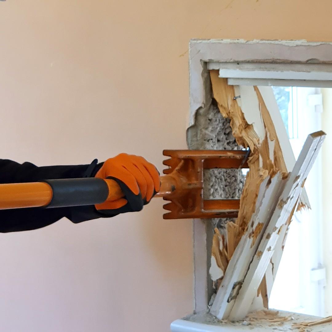 Demolition bar being used to destroy a window sill