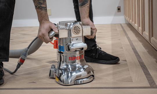 Person sanding a wood floor with an American Sanders tool